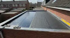 Plat dak met twee verschillende bitumen membranen naast elkaar: links een donkerblauwe APP-laag en rechts een grijze